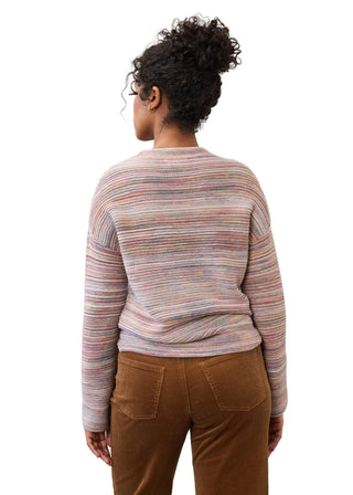 A woman viewed from behind wearing a long-sleeve knit sweater with thin multicolored horizontal stripes in pink, blue, yellow, and green, paired with brown pants, against a plain white background.