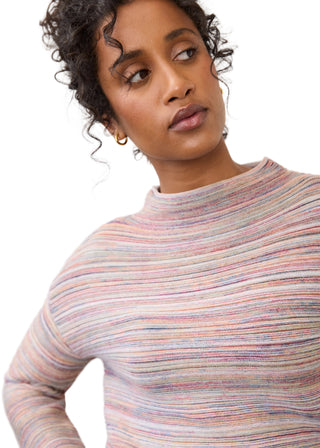 A close-up of a woman wearing a long-sleeve mock neck knit top with horizontal multicolor stripes in pink, blue, orange, and beige tones, set against a plain light gray background.