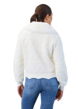 Person wearing a white quilted jacket and blue jeans on a light gray background