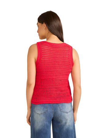 Woman wearing a red crochet top and blue jeans on a beige background