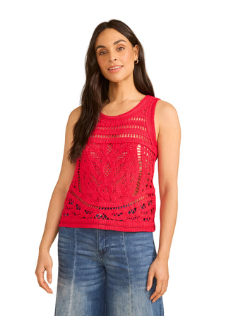 Woman wearing a red crochet top and blue jeans against a beige background