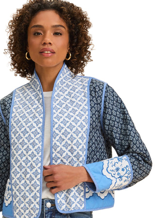 Woman wearing a blue and white patterned jacket on a beige background