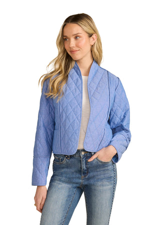 Woman wearing a blue quilted jacket and jeans on a beige background