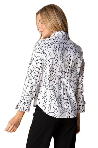 Woman wearing a white blouse with black geometric patterns on a beige background