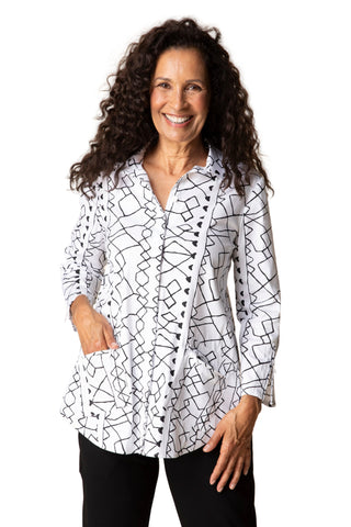 Woman wearing a white blouse with black geometric patterns on a beige background