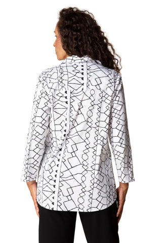 Woman wearing a white blouse with black geometric pattern on a beige background