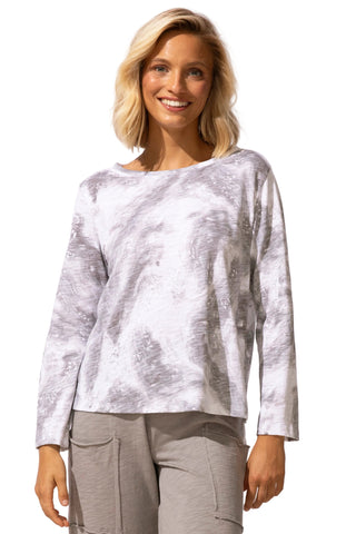 Woman wearing a white and gray patterned long-sleeve top with beige pants on a white background