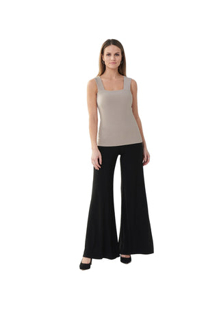 Woman wearing a beige sleeveless top and black flared pants on a white background