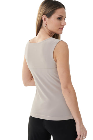 Woman wearing a beige sleeveless top on a white background