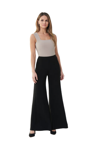 Woman wearing a beige top and black wide-leg pants on a white background