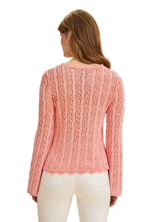 Woman wearing a pink knitted sweater against a beige background