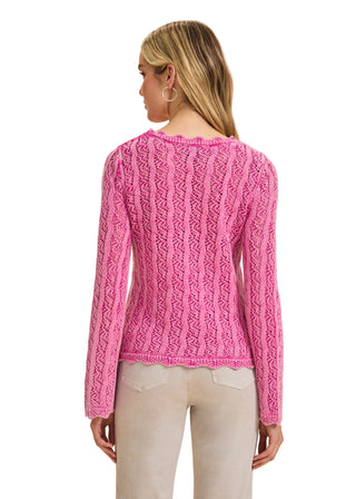 Woman wearing a pink cable knit sweater on a beige background