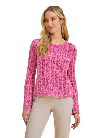 Woman wearing a pink cable knit sweater against a beige background