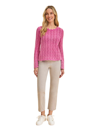 Woman wearing a pink knitted sweater and beige pants on a beige background