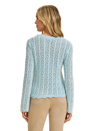 Woman wearing a light blue knitted sweater against a beige background