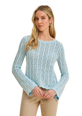 Woman wearing a light blue knitted sweater against a beige background