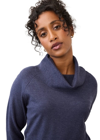 A woman wearing a heathered slate blue cowl neck sweater, photographed against a clean white studio background.