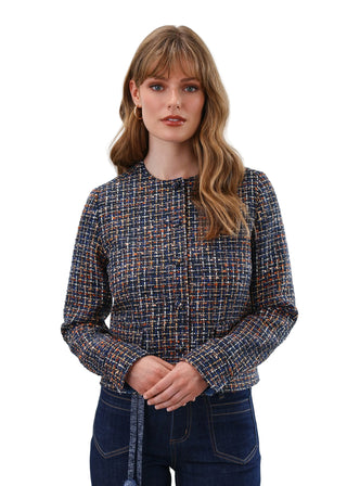 Woman wearing a patterned shirt and jeans against a plain background