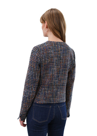 Woman wearing a patterned shirt and jeans on a plain background