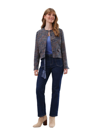 Woman wearing a plaid jacket, blue top, and dark jeans against a white background
