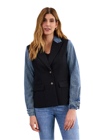 Woman wearing a black vest over a denim shirt with a plain background