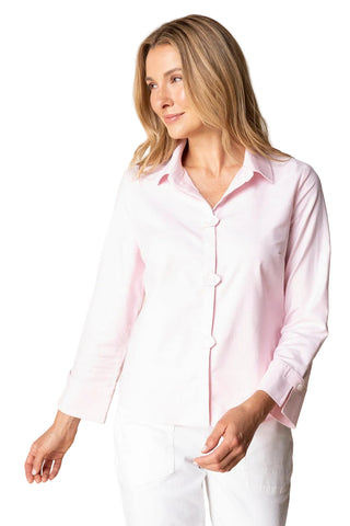 Woman wearing a light pink shirt and white pants against a beige background