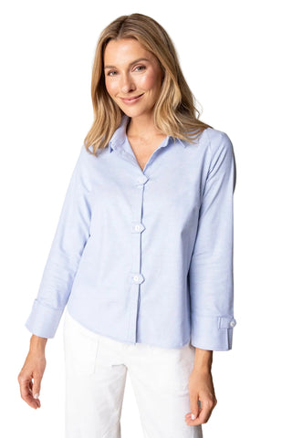 Woman wearing a light blue button-up shirt against a beige background