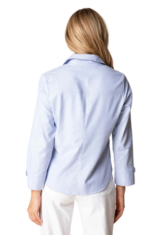 Person wearing a light blue button-up shirt and white pants on a beige background