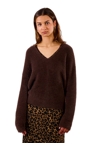 Woman wearing a brown sweater and leopard print skirt against a plain background
