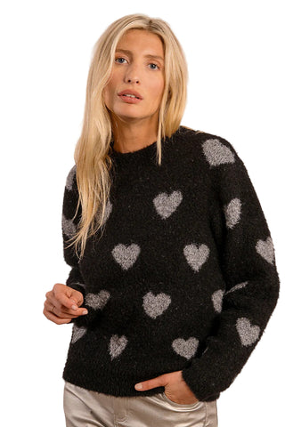 Woman wearing a black sweater with heart patterns on a beige background