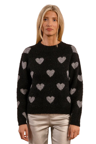 Woman wearing a black sweater with heart patterns on a beige background