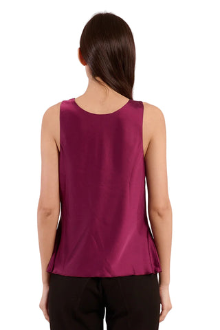 Woman wearing a sleeveless magenta top against a light pink background