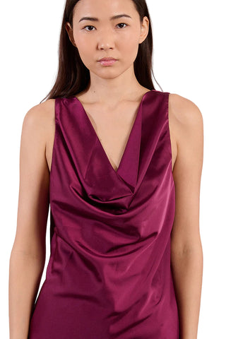 Woman wearing a burgundy satin dress against a pink background