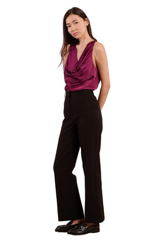 Woman wearing a sleeveless magenta top and black pants against a plain background