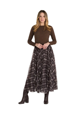 A woman modeling a brown long-sleeve knit top paired with a dark brown and black plaid pleated midi skirt and dark brown heeled boots, against a light gray studio background.
