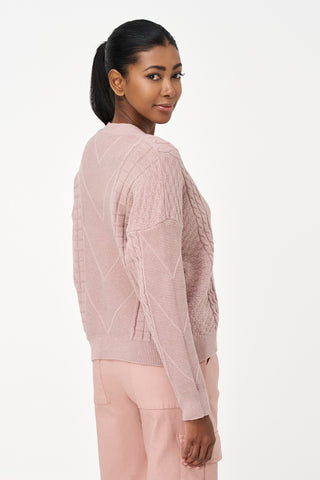 Woman wearing a light pink sweater and pants on a white background