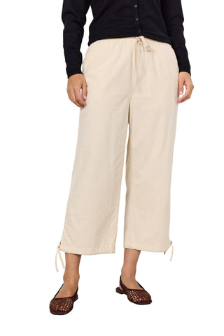 Person wearing beige wide-leg pants and a black top against a white background