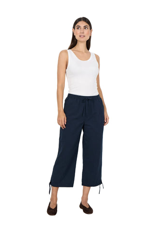 Woman wearing a white sleeveless top and navy wide-leg pants against a white background