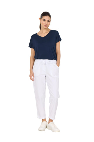 Woman wearing a navy blue top and white pants against a white background