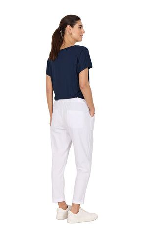 Woman wearing a navy blue top and white pants against a white background