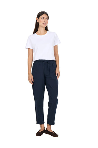 Woman wearing a white t-shirt and navy pants against a white background