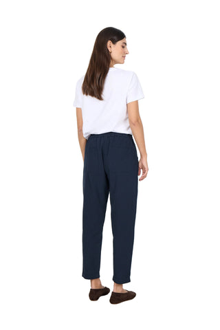Woman wearing a white shirt and navy pants against a white background