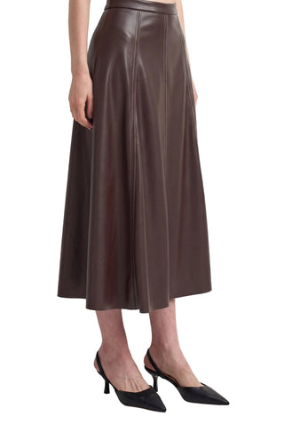 A model wearing a dark brown faux-leather midi skirt with black slingback pointed-toe heels, shown from the waist down against a plain white studio background.