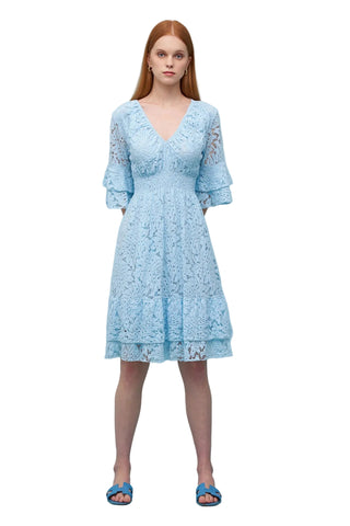 Woman wearing a light blue lace dress against a solid background