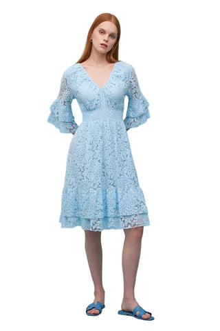 Woman wearing a light blue lace dress against a solid background