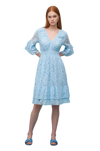 Woman wearing a light blue lace dress against a light blue background