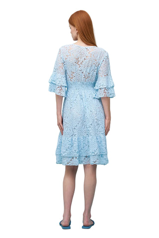 Woman wearing a light blue lace dress against a light blue background
