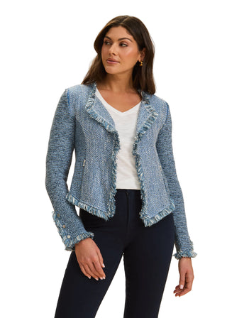 Woman wearing a blue textured jacket over a white shirt on a beige background