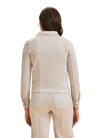 Person wearing a beige jacket and pants on a beige background