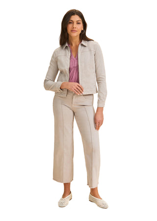 Woman wearing a light gray suit with a pink top on a beige background